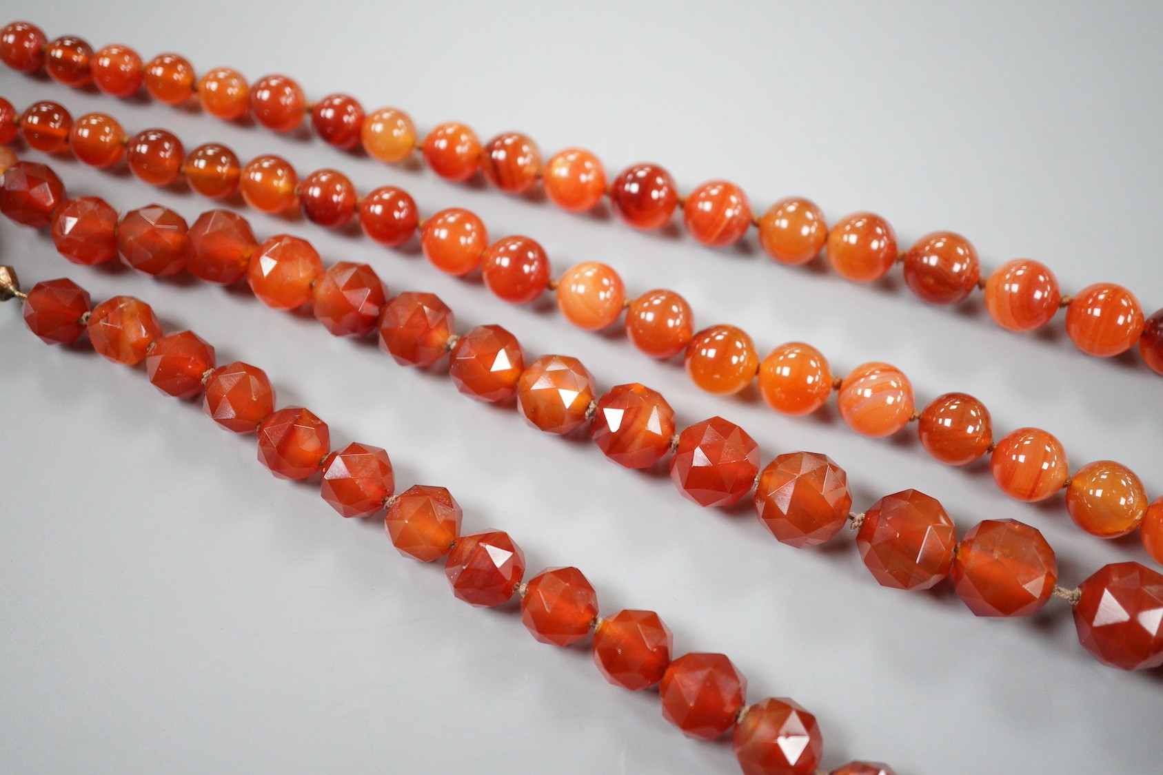 Two single strand carnelian necklace, one with facet cut beads, 44cm & 60cm, both with yellow metal clasps.